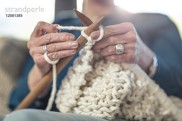 Seniorin beim Stricken auf der Couch zu Hause