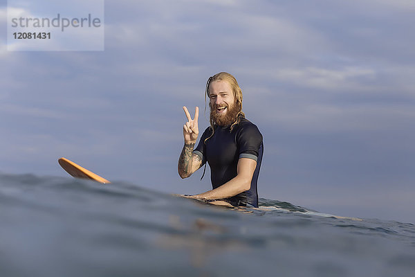Porträt eines glücklichen Mannes auf dem Surfbrett im Meer