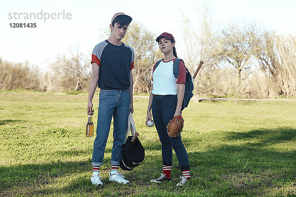 Portrait eines jungen Paares mit Baseballausrüstung im Park