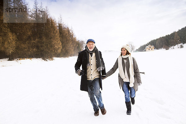 Glückliches Seniorenpaar beim Wandern in verschneiter Landschaft