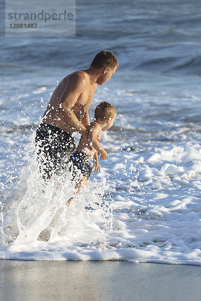 Indonesien  Bali  Vater und Sohn spielen im Ozean