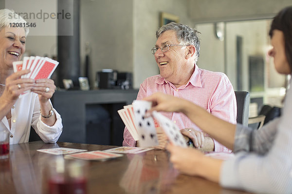 Seniorenpaar spielt Karten mit Tochter zu Hause