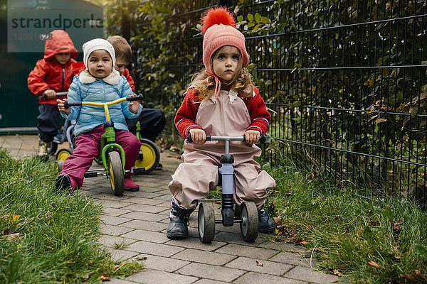 Kinder mit Rollern im Garten eines Kindergartens