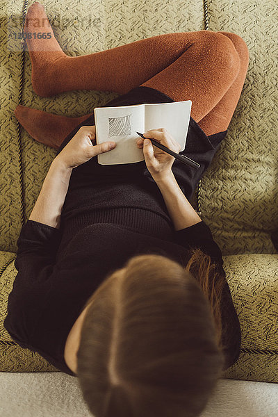 Frau auf der Couch sitzend  Zeichnung im Notizbuch  Draufsicht