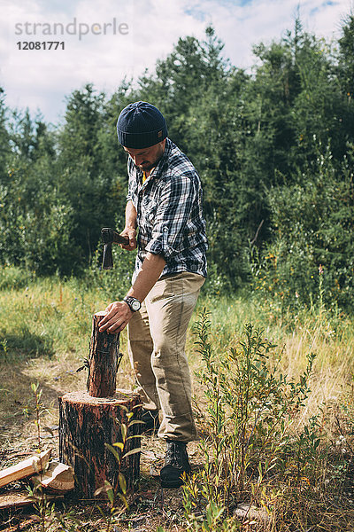 Mann hackt Holz in ländlicher Landschaft