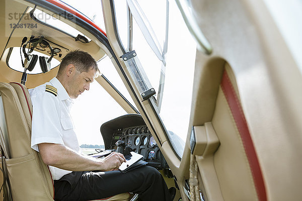 Pilot mit Tablett im Cockpit eines Hubschraubers