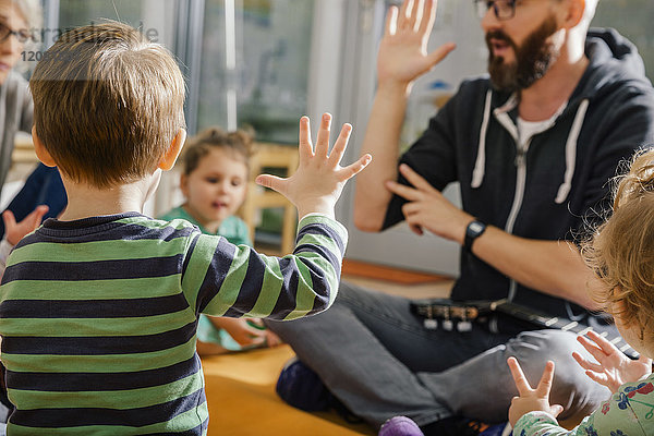 Kindererziehung beim Singen mit anderen und Erzieherin im Kindergarten