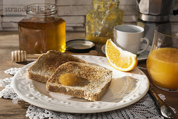 Frühstückstisch mit Toast  Orangenmarmelade  Honig  Orangensaft und Espresso