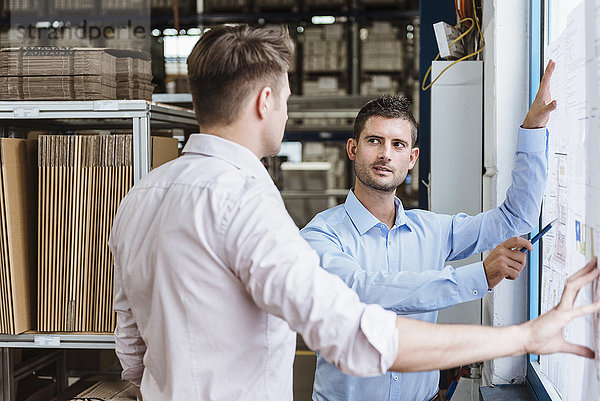 Geschäftsleute stehen am Fenster und diskutieren über Produktionspläne