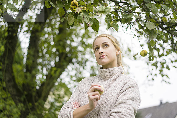 Porträt einer jungen Frau am Apfelbaum im Garten