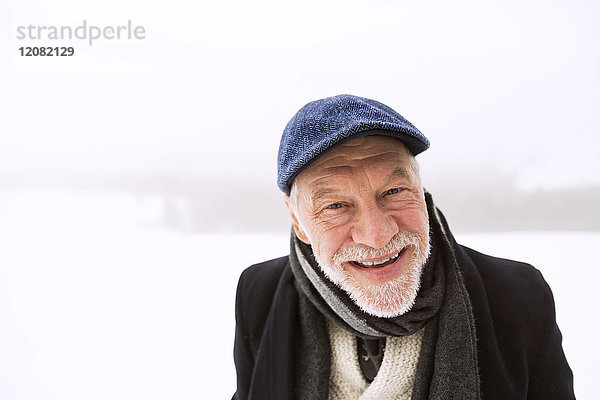 Porträt eines lachenden älteren Mannes im Schnee