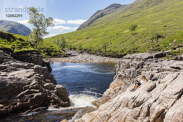 Großbritannien  Schottland  Schottische Highlands  Glen Etive mit River Etive und Glen Etive Falls  weibliche Touristenlektüre