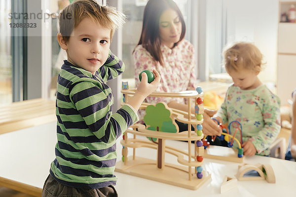 Junge schaut vom Spielen mit Spielzeug im Kindergarten auf