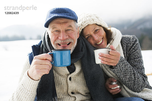Porträt eines Seniorenpaares mit heißen Getränken im Winter