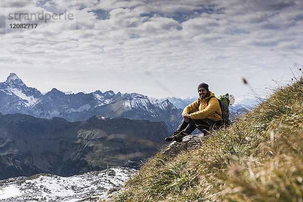 Deutschland  Bayern  Oberstdorf  lächelnder Wanderer sitzend in alpiner Landschaft