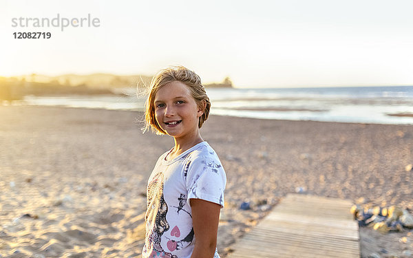 Porträt eines lächelnden blonden Mädchens am Strand
