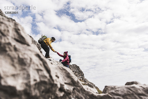 Deutschland  Bayern  Oberstdorf  Mann hilft Frau beim Klettern auf den Felsen