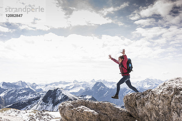 Deutschland  Bayern  Oberstdorf  Frau springt auf Felsen in alpiner Landschaft