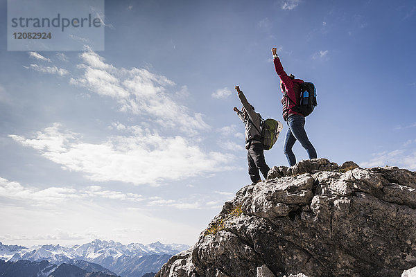 Deutschland  Bayern  Oberstdorf  zwei Wanderer  die in alpiner Landschaft auf den Felsen jubeln