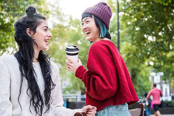 Zwei junge stilvolle Frauen lachen im Stadtpark