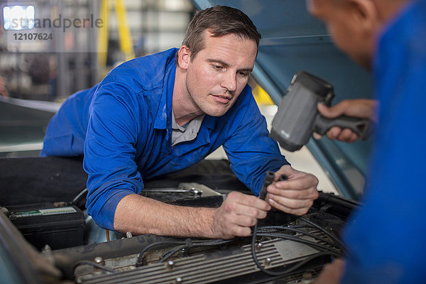 Automechaniker inspizieren Automotor in Reparaturwerkstatt