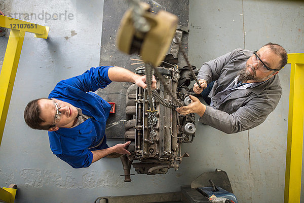 Draufsicht eines Automechanikers beim Anheben des Automotors in der Reparaturwerkstatt