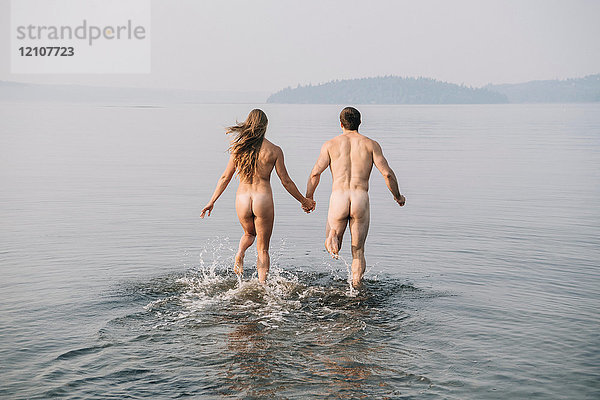 Rückansicht eines nackten Paares  das ins Wasser läuft