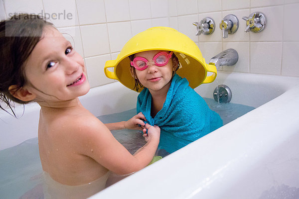 Mädchen hat Spaß beim Anziehen der Schwester in der Badewanne