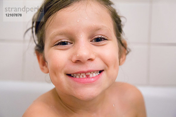 Porträt eines Mädchens mit fehlendem Zahn im Bad  lächelnd in die Kamera blickend