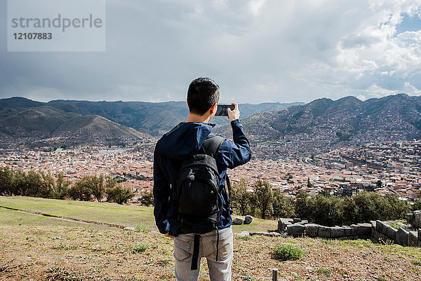 Mann fotografiert Blick aus Sacsayhuaman  mit Smartphone  Cusco  Peru  Südamerika