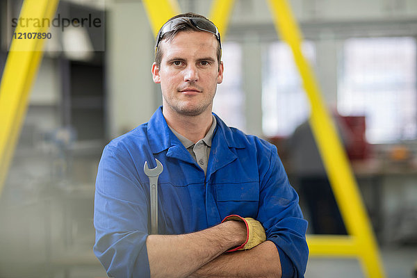 Porträt eines männlichen Automechanikers mit Schraubenschlüssel in der Reparaturwerkstatt