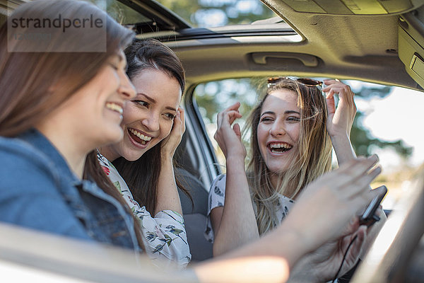 Drei junge Frauen im Auto  lachend
