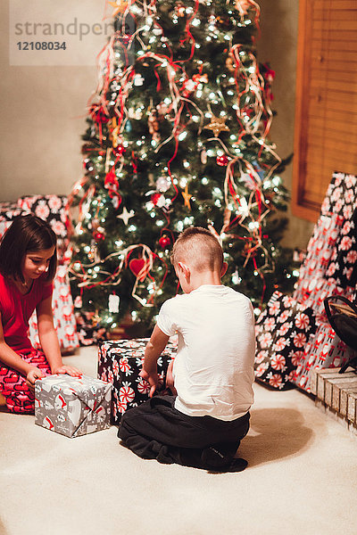 Brüder und Schwestern packen am Weihnachtstag Geschenke aus