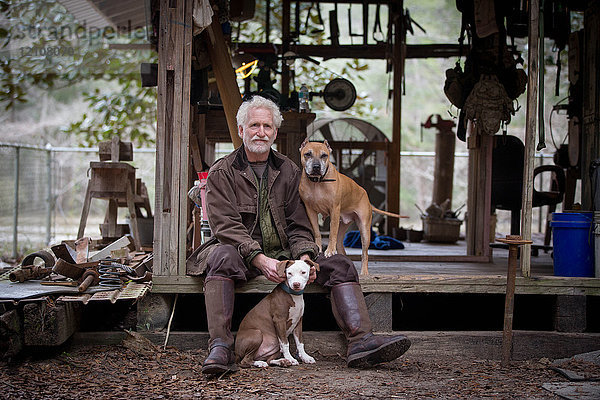 Mann mit Haushunden bei hölzerner Arbeitshütte