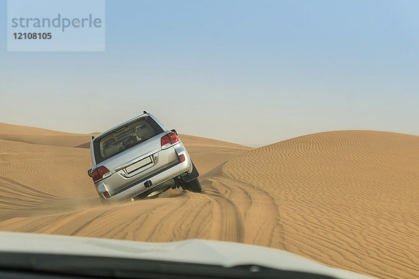 Geländefahrzeug fährt über steile Wüstendünen  Dubai  Vereinigte Arabische Emirate