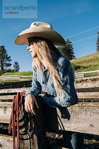 Cowgirl mit Cowboyhut  am Zaun lehnend  wegschauend  Enterprise  Oregon  Vereinigte Staaten  Nordamerika