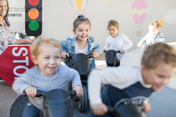 Jungen und Mädchen in der Vorschule  Motorradrennen schieben Motorräder im Garten