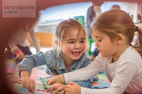 Zwei junge Mädchen  im Freien  spielen mit Schaumstoffpuzzlestücken