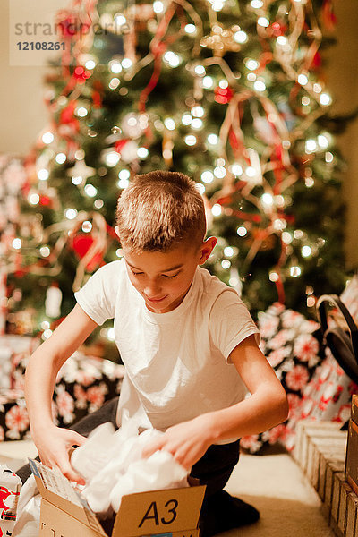 Junge packt Geschenk zu Weihnachten aus