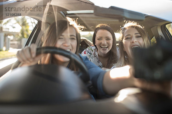 Drei junge Frauen im Auto  Fahrer stellt Navi am Fenster ein