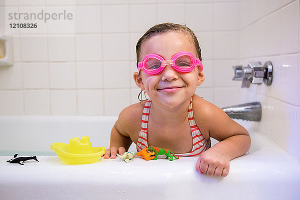 Porträt eines Mädchens mit Schwimmbrille in der Badewanne  das lächelnd in die Kamera schaut