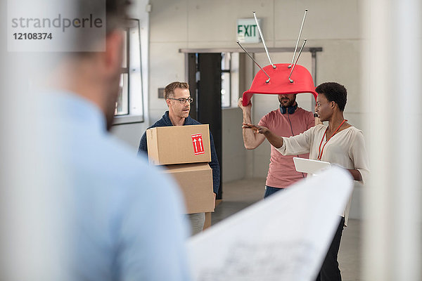 Kollegen im Büro  die Kartons und Stuhl tragen