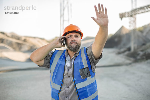 Steinbrucharbeiter im Steinbruch  mit Smartphone  Gesten mit der Hand