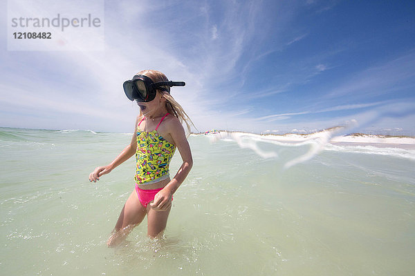 Mädchen mit Schwimmbrille  das im Meer watet