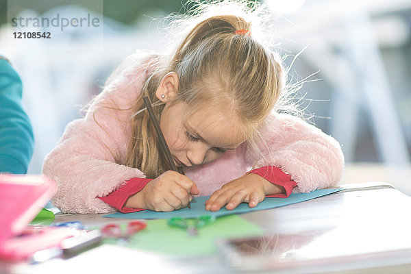 Junges Mädchen zeichnet auf farbigem Papier