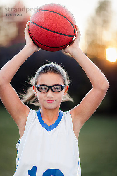 Porträt eines Mädchens mit Sportbrille  das Basketball hält