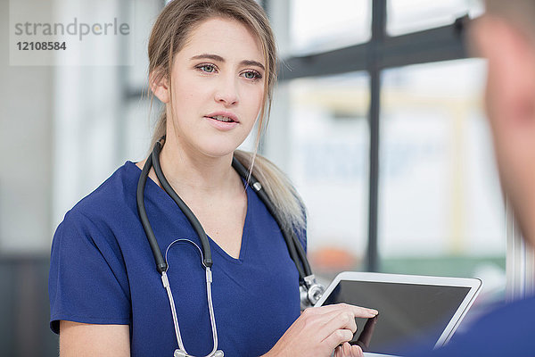 Männlicher und weiblicher Arzt im Gespräch  weiblicher Arzt mit digitalem Tablett