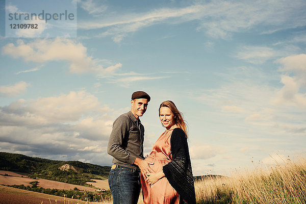 Porträt eines schwangeren Paares im mittleren Erwachsenenalter am ländlichen Hang