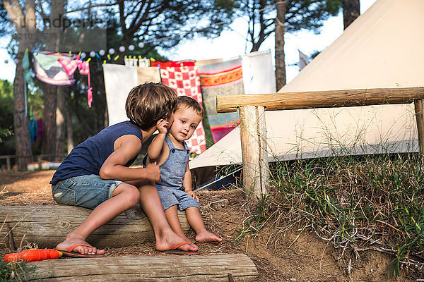 Männliches Kleinkind wird auf dem Campingplatz von seinem großen Bruder auf die Wange geküsst