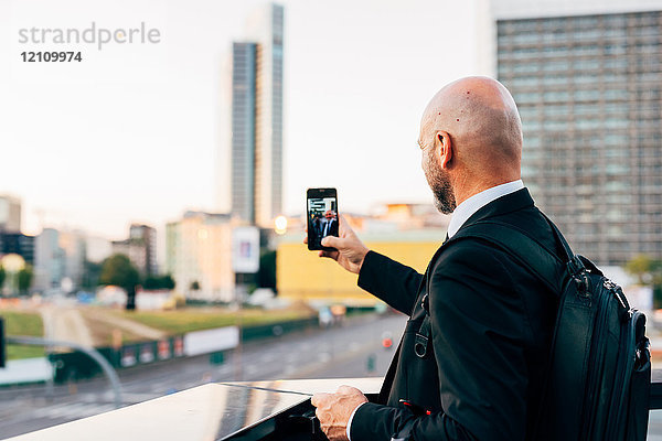Reifer Geschäftsmann  der im Freien steht  Selfie nimmt  Smartphone benutzt